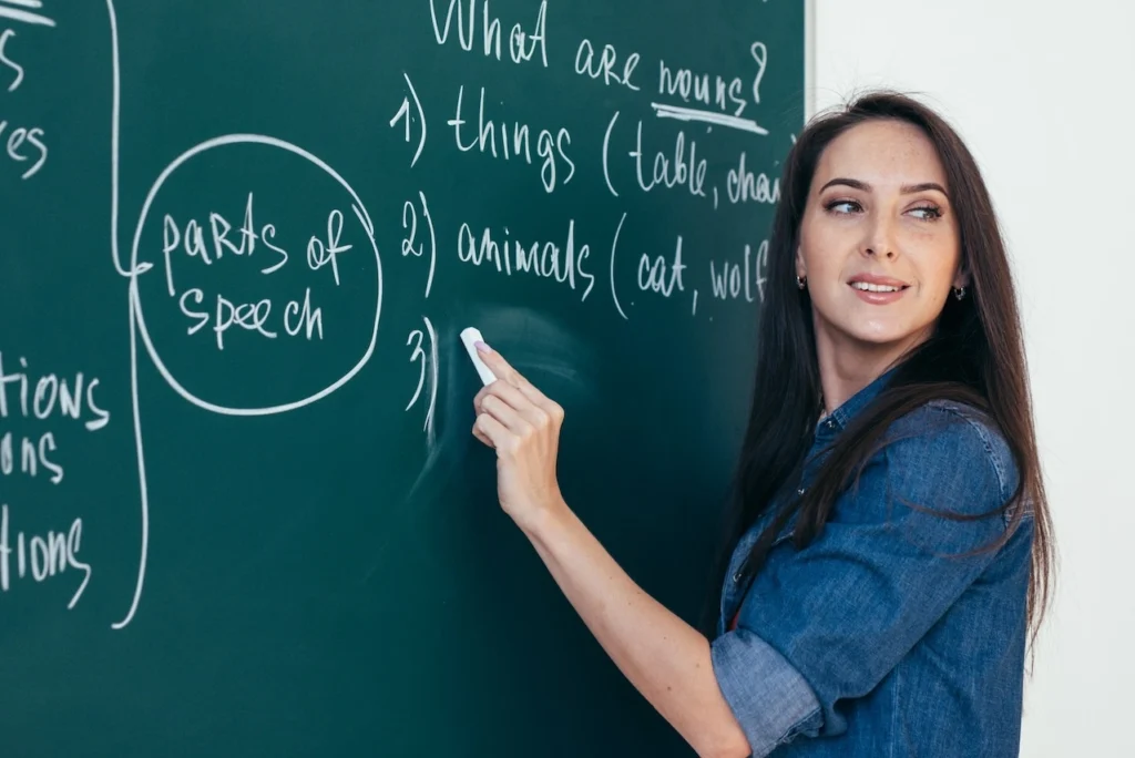 A female English teacher writing on a blackboard.