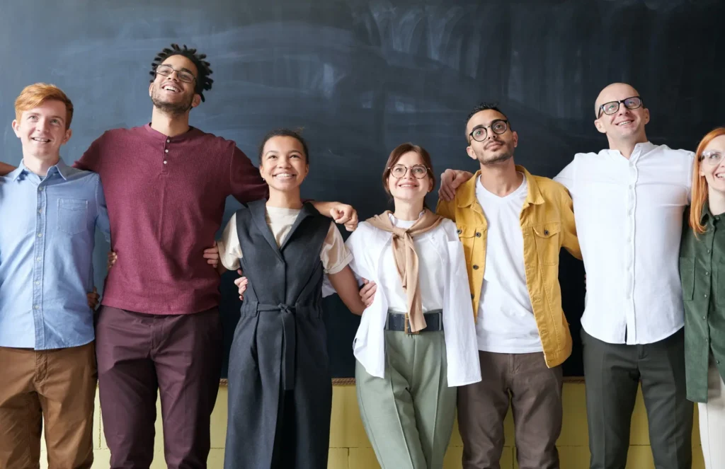 A group of culturally mixed people standing in front of a classroom blackboard.